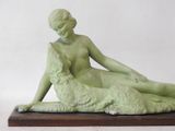 statue of a woman laying on a sheep on a wooden base