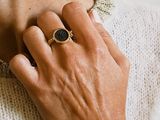 someone is wearing a gold ring with a black stone on it