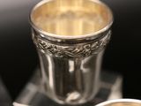 a silver cup sitting on top of a table next to other silver cups