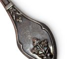 a silver spoon with a design on it on a white surface