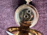 une montre de poche en or posée sur un tissu violet