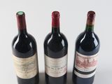 three bottles of red wine are lined up on a white surface