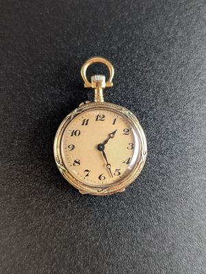 gros plan d'une montre de poche en or sur une surface noire