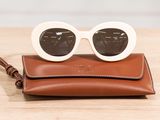 brown leather wallet with sunglasses on top of it on a wooden table