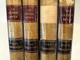 Quatre vieux livres sont alignés sur une étagère, avec une étiquette de prix