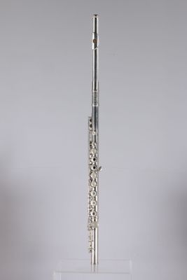 a silver flute on a clear stand against a gray background