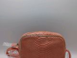 a pink snake skin bag with a white feather on the side