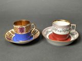 two cups and saucers with gold rims on a black surface