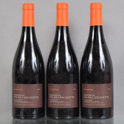 three bottles of red wine sit on a table in front of a gray background