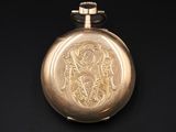 an antique gold pocket watch on a black surface with a black background