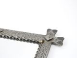 a metal cross on a white surface with a white background