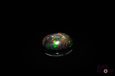 a black oplite with green and red speckles in the dark