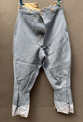 an old pair of jeans hanging on a hanger on a wall