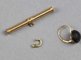 une image représentant une paire de boucles d'oreilles en or et un tube en or