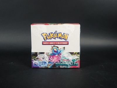 La boîte de cartes à collectionner Pokémon est posée sur une surface noire.