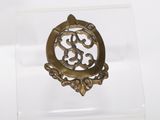an image of a gold brooch on a clear acrylic stand