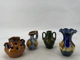 four different colored vases sitting on top of a white surface