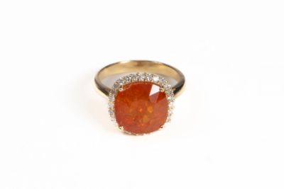 un gros plan d'une bague ornée d'une pierre orange entourée de diamants