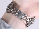 a woman wearing a silver bracelet with flowers on it