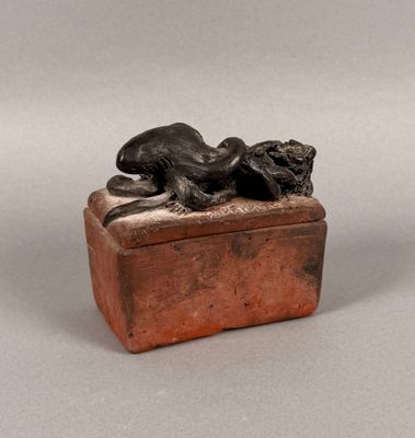 an image of a bronze statue of a dog laying on top of a box