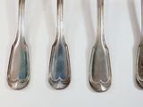 six spoons are lined up on a white surface