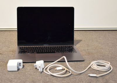 un ordinateur portable posé par terre à côté d'un chargeur et d'un chargeur