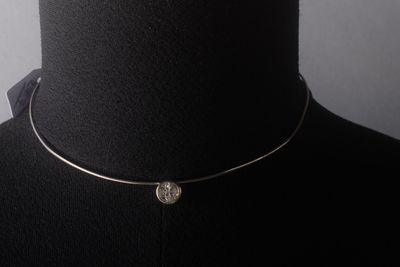 un gros plan sur un mannequin portant un collier orné d'une pièce de monnaie