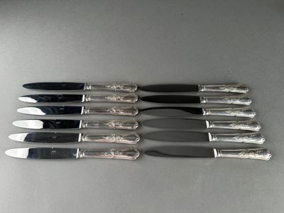 six couteaux sont alignés sur une table