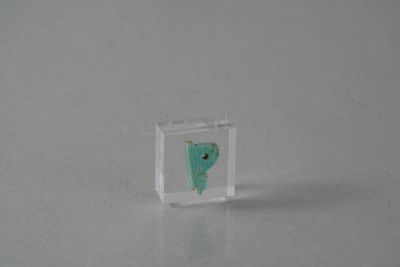 a small piece of glass with a green face inside of it