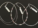 three silver bracelets with pink and blue beads on a black background