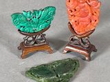 trois pièces de jade et de corail sculpté, présentées sur un socle