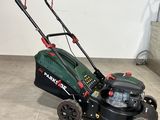 une tondeuse à gazon verte et noire posée sur le carrelage d'une pièce