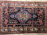 un tapis posé sur un parquet, orné d'un motif bleu et rouge