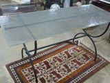 une table avec un plateau en verre et un tapis posé au sol