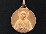 a close up of a gold medal with an image of the virgin mary