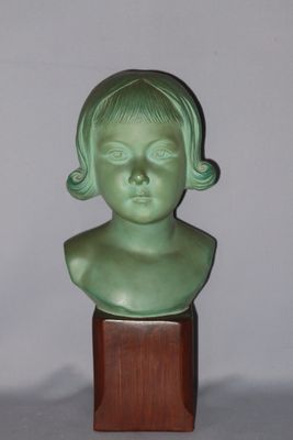 a small green bust of a child on a wooden stand