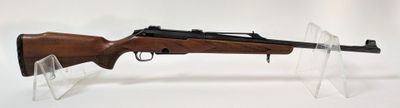 gros plan d'un fusil posé sur un support sur une surface blanche