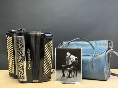 une vieille photo d'une femme jouant de l'accordéon à côté d'un sac à main bleu