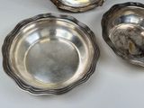 three silver dishes sitting on a white table with a white table cloth