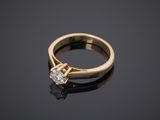 a single stone diamond ring on a black surface