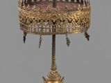 a gold cake stand with a statue on top of it
