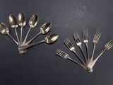 six fourchettes et cuillères sont disposées en rangée sur une surface noire