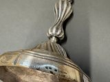 an old silver bell hanging from a wall on a gray surface