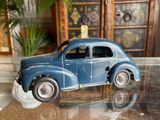 a blue toy car sitting on a table next to a potted plant