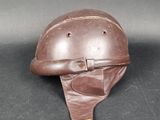 un vieux casque en cuir muni d'une lanière en cuir, posé sur une surface noire