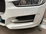 the front end of a white jaguar car parked on the side of the road