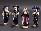 three figurines of people dressed in different outfits and hats