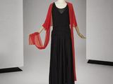 un mannequin vêtu d'une robe noire et d'une cape rouge