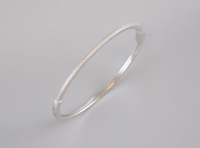 a close up of a silver bang bracelet on a white background