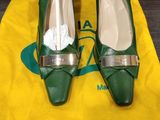 une paire de chaussures vertes posées sur un sac jaune, posé sur un plancher en bois